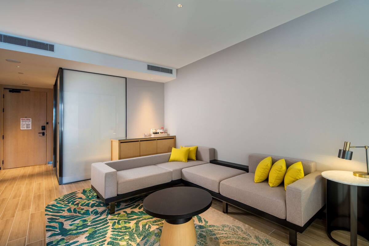 A modern living room with a sectional sofa, a round coffee table, and a small side table with a lamp.