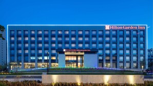 Ein Hilton Garden Inn Hotel mit moderner Fassade, mehreren Etagen und einem gut beleuchteten Eingang.