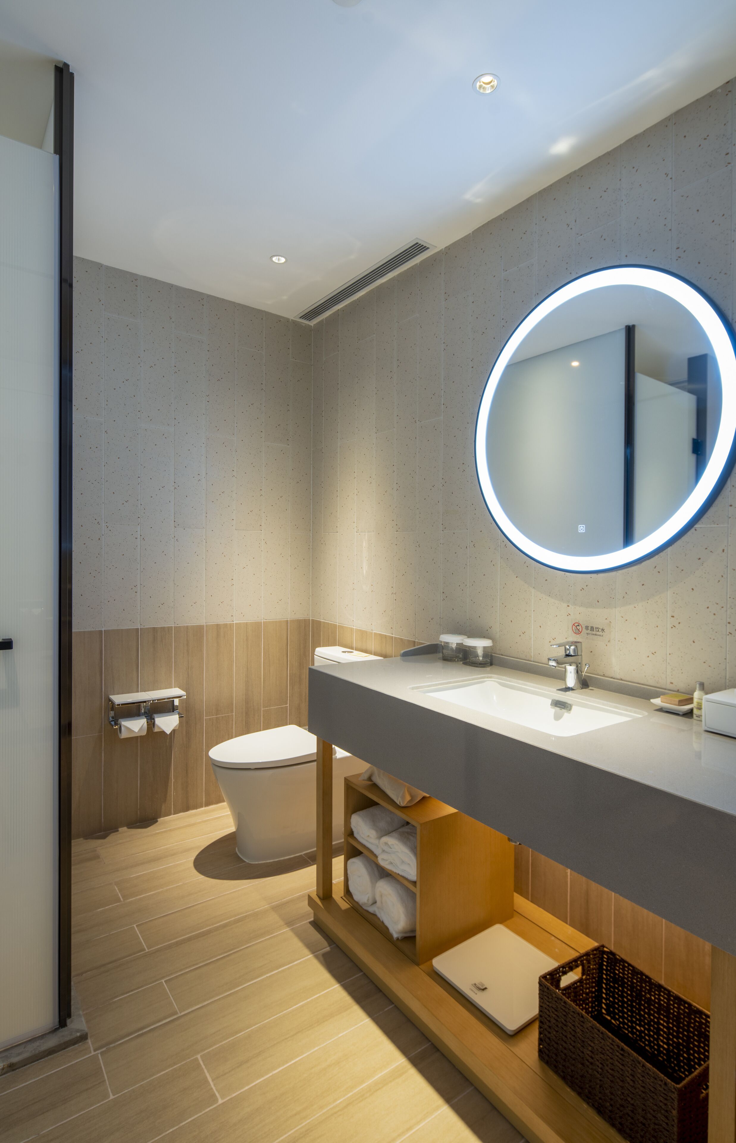 A modern bathroom with a round mirror, a toilet, and a sink.