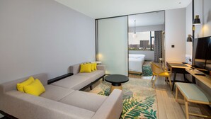 A modern hotel room with a sofa, a dining table, and a TV. - Hilton Garden Inn Changchun Economic Development Zone (Changchun)