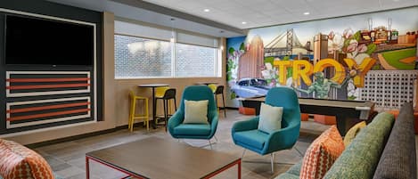 A modern lounge area with teal armchairs, a sofa, and a coffee table.