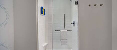 A modern shower with a glass door, a towel rack, and a small shelf.