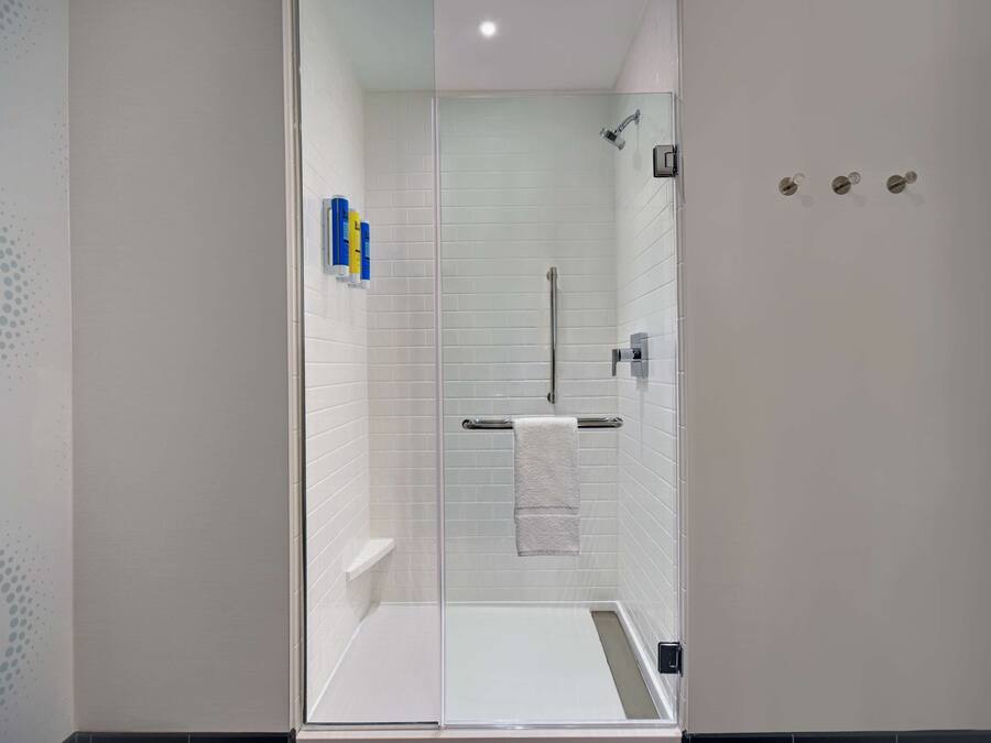 A modern shower with a glass door, a towel rack, and a small shelf.