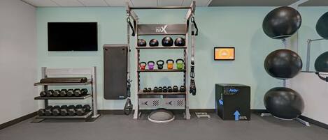 A gym with a pull-up bar, kettlebells, dumbbells, and exercise balls.