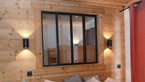 A wooden-paneled room with a bed, pillows, and two wall-mounted lights. - 5pers. Running boards Modern Mountain View (Valmeinier)
