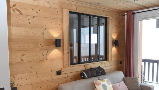 A cozy room with a wooden ceiling, a sofa with cushions, a small table, and a window with blinds. - 5pers. Running boards Modern Mountain View (Valmeinier)
