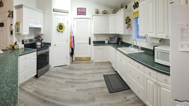 A kitchen with white cabinets, a microwave, and a sink. There is a welcome sign on the door and a sign that says "Kiss Cook". - Large, comfortable home in Pocatello (Pocatello)