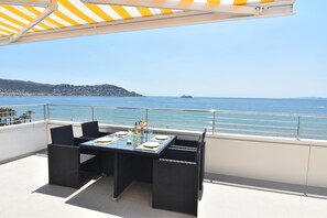A terrace with a table set for two, overlooking a coastal view. - Charming apartment for rent in Roses, Costa Brava! 0 meters from the beach. Enjoy the community pool and sea views. (Roses)