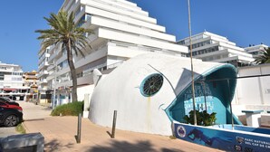 Un edificio moderno con un diseño arquitectónico único y redondeado, que presenta un amplio ventanal y un mural azul en la fachada.