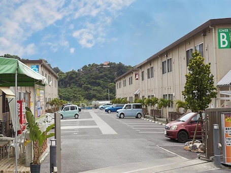 A street view with parked cars, a crosswalk, and buildings labeled 'TOWER B' and 'TOWER A'.