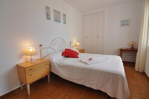 A neatly arranged bedroom with a bed, bedside tables, and a wardrobe.