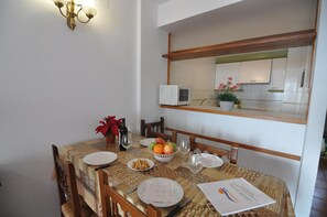 A dining table set with plates, glasses, a bowl of fruit, and a bottle of wine.