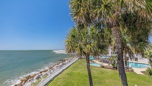 Une propriété située en bord de mer, dotée d’une piscine, d’une clôture blanche et de palmiers.