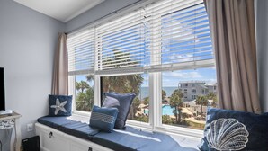 Une chambre avec un coin fenêtre, une télévision et une vue sur une piscine et des bâtiments.