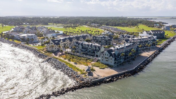 Une station balnéaire avec des immeubles à plusieurs étages, une promenade en bord de mer et un terrain de golf en arrière-plan.
