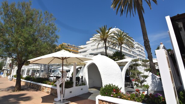 Ein Resort mit Außenbereich, Palmen und einem weißen Gebäude mit mehreren Balkonen.