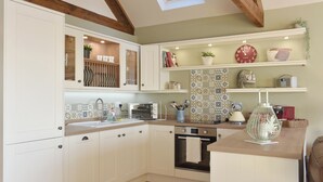 A modern kitchen with white cabinetry, a skylight, and a variety of decorative items on the shelves. - 2 bedroom accommodation in Sedgefield (Sedgefield)