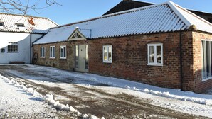 A brick building with a snow-covered roof and a small porch. - 2 bedroom accommodation in Sedgefield (Sedgefield)