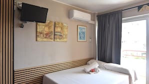 Ein Hotelzimmer mit Bett, Flachbildfernseher, Klimaanlage und Kunstwerken an der Wand.