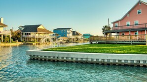 A waterfront property with a grassy area, a dock, and multiple buildings with balconies and a covered walkway. - Coastal Class Waterfront - "Your Home away from Home" (Rockport)
