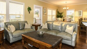 A living room with a sectional sofa, a coffee table, and a dining area with a table and chairs. - Coastal Class Waterfront - "Your Home away from Home" (Rockport)