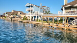 A waterfront property with multiple houses, a dock, and a covered area with outdoor seating. - Coastal Class Waterfront - "Your Home away from Home" (Rockport)