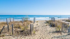 Una playa arenosa con cercas de madera y un cielo azul despejado.