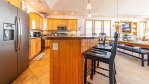 Una cocina con armarios de madera, un refrigerador de acero inoxidable, un microondas e una isla central con taburetes de bar.