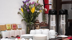 A breakfast setup with coffee and milk dispensers, a small house-shaped decoration, and a variety of breakfast items on a table. - Cusco Plaza Saphi (Cusco)