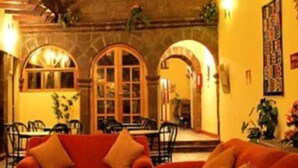 A cozy interior with a red sofa, a dining area with a table and chairs, and a stone wall. - Cusco Plaza Saphi (Cusco)
