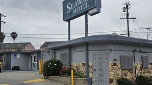A Seaway Motel with a sign, a parking lot, and a building with a stone facade. - Seaway Motel (Los Angeles)