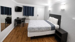 Una habitación de hotel con cama, escritorio, silla, televisión y puerta.