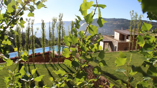 A view of a building with a pool, surrounded by greenery and hills in the background. - Heavenly Duplex with 2 gardens at Redrock Faqra (faqra)