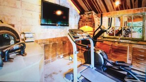 Un gimnasio en casa con equipo de ejercicio, un televisor y una zona de cocina.