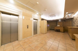 Enter a stylish lobby with a reception desk, elevators, and patterned wallpaper.