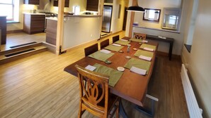 A spacious kitchen with wooden cabinetry, a central island, and a dining area with a long table and chairs. - Modern Downtown Loft in Heart of Silverton (Silverton)