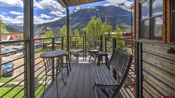 A wooden balcony with a view of mountains and a parking lot. - Modern Downtown Loft in Heart of Silverton (Silverton)