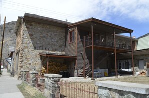 A two-story building with a stone facade, a wooden upper level with a balcony, and a staircase leading to the upper floor. - Modern Downtown Loft in Heart of Silverton (Silverton)