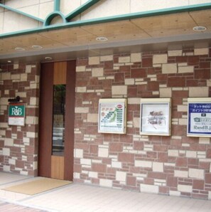 A building entrance with a brick wall, a wooden door, and a mat at the entrance.