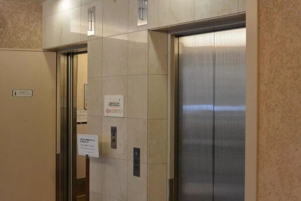 An elevator with a metallic interior and a glass door, accompanied by a sign on the wall.