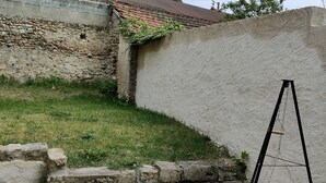 Un jardin avec une balançoire, un muret en pierre et une pelouse.