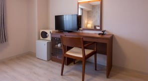 A room with a wooden desk, a chair, a television, and a small refrigerator.