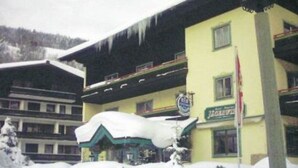 Un hotel amb façana groga, un cartell i un teulat cobert de neu.
