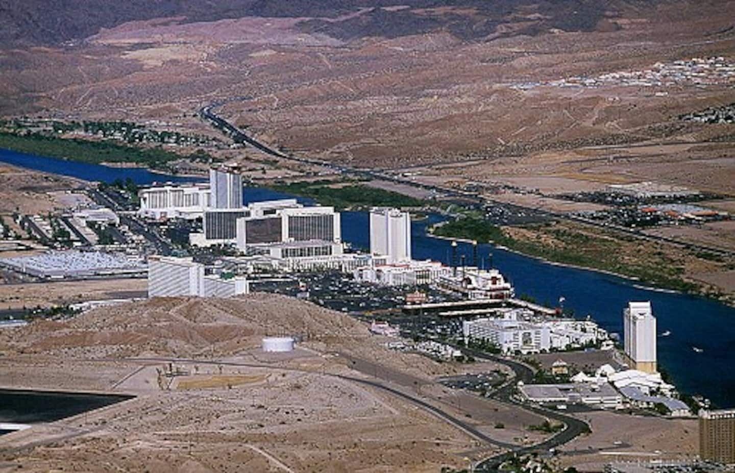 Un vaste complexe industriel comprenant plusieurs bâtiments, une rivière et un paysage montagneux en arrière-plan.