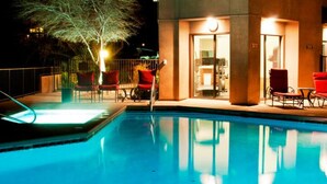A swimming pool with red chairs and a building with a glass door. - AFFLUENCE ABOUNDS ~ FOOTHILLS CONDO ~ SLEEPS 6 (Tucson)