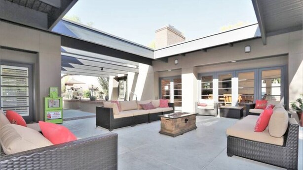 An outdoor patio area with wicker furniture, a wooden coffee table, and a green vending machine. - AFFLUENCE ABOUNDS ~ FOOTHILLS CONDO ~ SLEEPS 6 (Tucson)