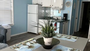Eine Küche mit weißen Schränken, einem Kühlschrank und einer Kaffeemaschine auf der Arbeitsfläche.
