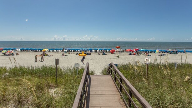 Ein Strand mit einer Holzpromenade, die zum Ufer führt, mit einem Schild, auf dem 'KEEP OFF DEDICATED' steht.