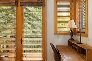 A room with a wooden bench, a table, and a lamp. - Outpost: Moose Creek 16 - Private Hot Tub! (Teton Village)