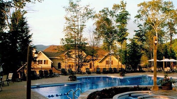 Relax by the pool surrounded by lush trees and a hilly backdrop.